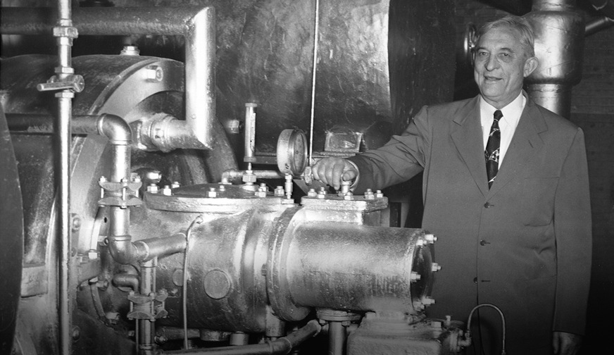 Willis Carrier im Jahr 1950 mit der ersten je gebauten Turbokältemaschine, die anschließend 27 Jahre lang bei der Onondaga Pottery Company in Syracuse, New York, zuverlässige Dienste leistete. Die Carrier Corporation kaufte das Gerät zurück, um es der Smithsonian Institution in Washington D.C. zu übergeben, wo es heute zu sehen ist.
