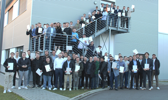 Alt-Text: „Gruppe von Fachleuten aus der Kälte- und Klimatechnik mit Zertifikaten auf einer Treppe eines modernen Gebäudes, die neueste Entwicklungen in Kälteerzeugung und Energiemanagement feiern.“.