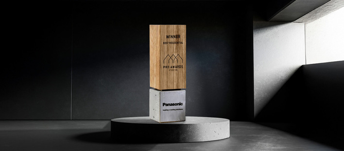 Alt-Text: „Holz- und Betonskulptur in Form eines Preises für ‚Bestes Wohnprojekt‘, präsentiert von Panasonic, auf einem runden Podest. Diese Auszeichnung steht symbolisch für herausragende Leistungen in der Kälte- und Klimatechnik im Wohnsektor. - © Panasonic © Panasonic