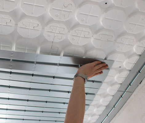 Optimierter Alt-Text: „Montage einer Traversenschiene für ein Kälteleitungs- oder Lüftungskanalsystem an einer abgehängten Akustikdecke in einem Technikraum.“. - © Bild: Schütz