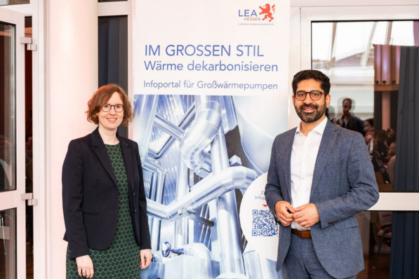 Zwei Personen stehen lächelnd vor einem Schild über die Dekarbonisierung von Wärme mit Großwärmepumpen. - © Landesenergieagentur Hessen © Landesenergieagentur Hessen