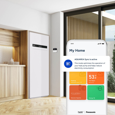 Auf dem Smartphone ist AQUAREA Sync aktiv und optimiert eine Wärmepumpe in einer modernen Küche mit großen Fenstern. - © Panasonic / tado © Panasonic / tado