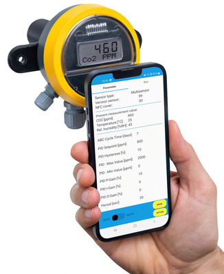 Eine Hand hält ein Smartphone mit Sensordaten in der Nähe eines CO2-Messgeräts, das 460 PPM anzeigt. - © Bild: Oppermann